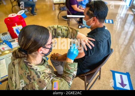 SPC. Soares, uno specialista medico di combattimento assegnato alla Task Force Kauai, Hawaii National Guard Joint Task Force, amministra il vaccino COVID-19 ai residenti Kauai idonei alla Sala della Convenzione Kauai War Memorial, 25 marzo 2021, Kauai, Hawaii. Soares e medic del collega, SPC. Hezekiah J. Pacheco assiste l'Ufficio sanitario del distretto di Kauai con in-processing e vaccinazioni. I medici da soli hanno inoculato più di 200 residenti con il vaccino moderna nel tentativo di aiutare la contea a mitigare le minacce immediate alla vita derivanti da COVID-19. Foto Stock