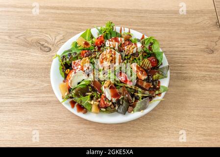 Insalata di capra con pezzi di cotogna, semi di girasole, noci tritate, uvetta e teneri germogli di lattuga e spinaci, conditi con olio e balsamo Foto Stock