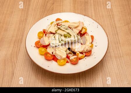 Insalata con pomodori ciliegini, pomodori regolari, cetriolini sottaceto, ventre di tonno e erba cipollina sottaceto Foto Stock