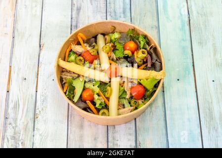 insalata con asparagi bianchi, olive snocciolate, pomodori ciliegini, bonito settentrionale in scatola e tiri di lattuga assortiti con carote su una ciotola di cartone per ho Foto Stock