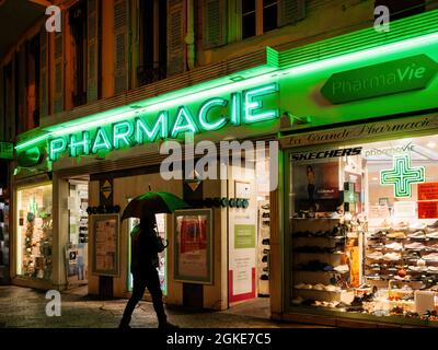 Uomo singolo con ombrello di fronte al negozio di droga farmacia Foto Stock