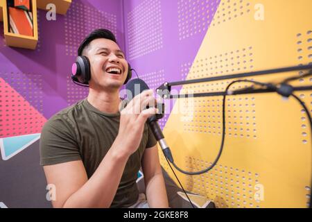 happy asian uomo sta registrando un podcast nel suo studio Foto Stock