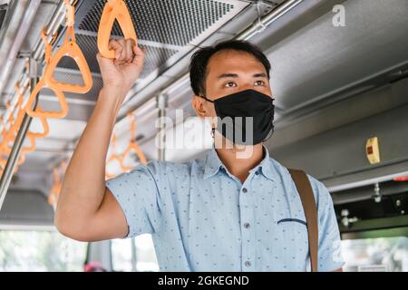 operatore asiatico indossare maschera per la protezione nei trasporti pubblici. Passeggeri in tram Foto Stock