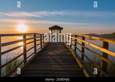 tramonto sul lago, molo di legno e una piattaforma di osservazione coperta Foto Stock