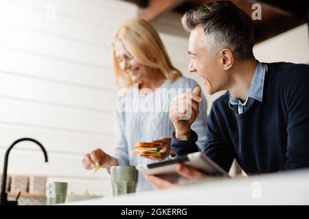 Coppia moglie e marito che hanno fatto colazione la mattina prima di lavorare, lavorando su un tablet