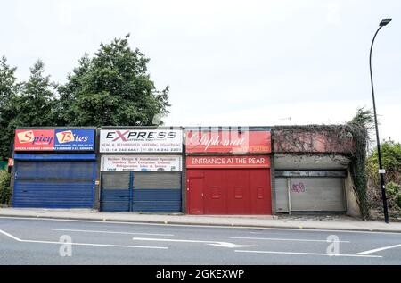 Una fila di negozi semi derelitti e decadenti in un angolo industriale del centro di Sheffield. Foto Stock