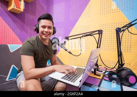 happy asian uomo sta registrando un podcast nel suo studio Foto Stock