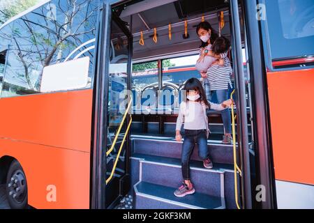 madre asiatica che porta sua figlia a scuola con autobus di trasporto pubblico Foto Stock