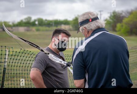 U.S. Marine staff Sgt. Eric Haiser rivede la sua impostazione di campo d'azione con l'assistenza di Steve Arnold, allenatore volontario dell'arco, come parte della pratica di competizione di tiro con l'arco del Guerriero ferito e del fiocco, 5 aprile 2021, alla base congiunta di San Antonio - Fort Sam Houston, Texas. Storicamente, gli annuali Marine Corps Trials promuovono il recupero e la riabilitazione attraverso la partecipazione sportiva adattativa e sviluppano cameratismo tra i membri di servizio e i veterani di recupero. È un'opportunità per gli RSM di dimostrare i loro risultati e serve come sede principale per selezionare i partecipanti del corpo Marino per il DoD W. Foto Stock