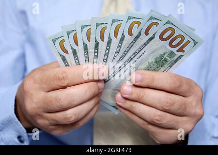 DOLLARI USA in mani maschili primo piano, uomo in abiti business contando i soldi. Concetto di salario, tangente, assistenza finanziaria o prestito Foto Stock