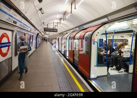 Stazione della metropolitana di Kings Cross - un passeggero che indossa una maschera durante la pandemia COVID 19 e un treno della metropolitana, London UK Foto Stock