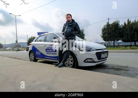 Kemerburgaz, Istanbul, Turchia - 03.19.2021: Bell'istruttore di test di guida in Turchia in piedi davanti alla sua vettura di test sotto il cielo blu. Trasl Foto Stock