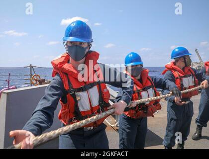 I marinai DEL MARE FILIPPINO (7 aprile 2021) erigono una linea sul fantastico cacciatorpediniere missilistico guidato di classe Arleigh Burke USS Mustin (DDG 89) durante un rifornimento in mare. Mustin è assegnato alla Task Force 71/Destroyer Squadron (DESRON) 15, la più grande DESRON della Marina e la principale forza di superficie della 7a flotta statunitense. Foto Stock