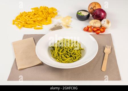 Ricetta italiana di spaghetti al pesto con pomodori, cipolle, aglio e pasta fresca su tovaglie di carta Foto Stock