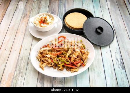 set di ingredienti per preparare fajitas di pollo con peperoni saltati, riso bianco con pico de gallo e tortillas di mais su tavola di legno Foto Stock