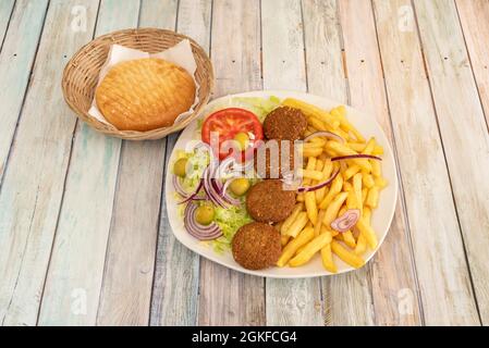 Menu di falafel su piatto con patate e insalata, pita pane, olive e cipolla a base di kebab ristorante Foto Stock