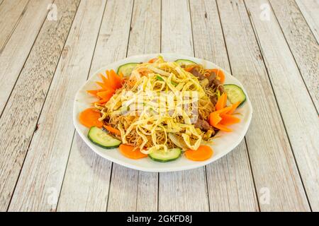 Spaghetti di riso speciali con verdure e carne saltati nel wok su un piatto bianco Foto Stock