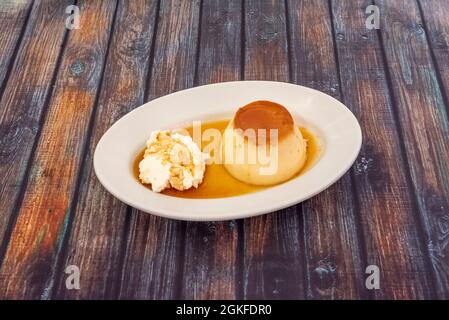 Deliziosa crema alle uova con gelato alla vaniglia e succo di caramello su un vassoio bianco Foto Stock