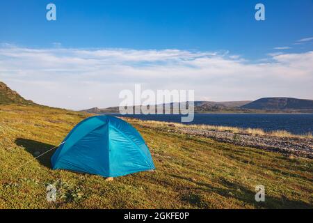 Camping tenda al campeggio panoramico sulla costa dell'Oceano Artico con la catena montuosa in background - concetto di campeggio selvaggio Foto Stock