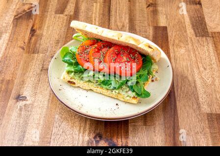 Sandwich di focaccia vegetale con eccellenti pomodori, pane tostato spalmato con verdure e lattuga in quantità Foto Stock