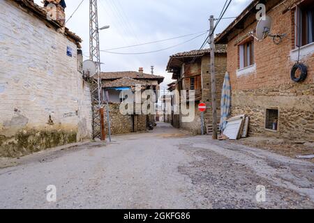 Birgi, Izmir, Turchia - 03.09.2021: Case in pietra e adobe nel villaggio di Birgi e locale strada tradizionale sotto il cielo blu con spazio copia Foto Stock