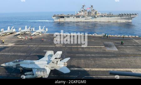 SOUTH CHINA SEA (9 aprile 2021) – il gruppo Theodore Roosevelt Carrier Strike Group transita in formazione con il Makin Island Amphibious Ready Group nel South China Sea 9 aprile 2021. Il Theodore Roosevelt Carrier Strike Group, il Makin Island Amphibious Ready Group e l'incrociatore missilistico guidato di classe Ticonderoga USS Port Royal (CG 73) stanno conducendo operazioni di forza d'attacco rapida durante le loro dispiegazioni nell'area operativa della 7a flotta. Come la flotta più grande della Marina degli Stati Uniti, 7th Fleet opera regolarmente e interagisce con 35 nazioni marittime, mentre conducendo missioni per p Foto Stock