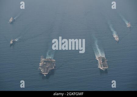 SOUTH CHINA SEA (9 aprile 2021) il gruppo Theodore Roosevelt Carrier Strike Group transita in formazione con il Makin Island Amphibious Ready Group nel South China Sea 9 aprile 2021. Il Theodore Roosevelt Carrier Strike Group, il Makin Island Amphibious Ready Group e l'incrociatore missilistico guidato di classe Ticonderoga USS Port Royal (CG 73) stanno conducendo operazioni di forza d'attacco rapida durante le loro dispiegazioni nell'area operativa della 7a flotta. Come la flotta più grande della Marina degli Stati Uniti, 7th Fleet opera e interagisce di routine con 35 nazioni marittime mentre conducendo missioni per la prefinale Foto Stock