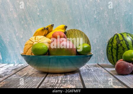 Vassoio di bambù blu con frutta fresca di stagione. Meloni di Piel de sapo, manga e banane mature, pesche e cocomeri. Foto Stock