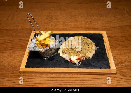 Piccola milanese argentina con cipolla, pomodoro, origano, pomodoro e un lato di patate fritte Foto Stock