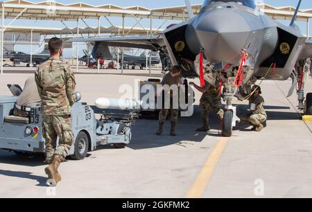 I manutentori assegnati alla 61a unità di manutenzione degli aeromobili caricano un missile aria-aria a medio raggio inerte AIM-120 su un velivolo F-35A Lightning II durante una gara di carico, il 9 aprile 2021, alla base dell'aeronautica di Luke. Nelle competizioni di carico, il lavoro di squadra è essenziale per il successo dell'equipaggio e per la missione generale. Attraverso una competizione amichevole, il 56o Gruppo di manutenzione migliora la letalità e la prontezza degli aerei e dei manutentori di Luke. Foto Stock