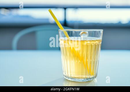 Sorseggiando un succo di ananas servito in un bicchiere di cristallo su una terrazza al tramonto Foto Stock