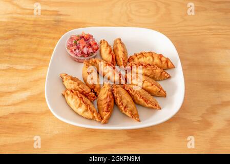 Grande porzione di gnocchi cinesi farciti di carne, gyozas, fritti in olio e guarniti con verdure tritate Foto Stock