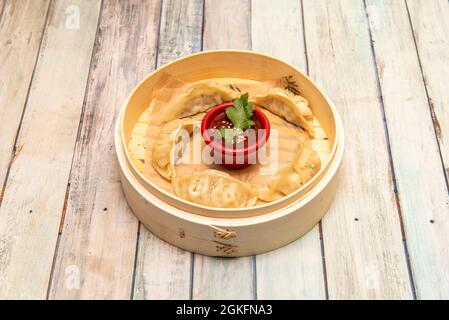 Gnocchi giapponesi, gyozas, cotti al vapore in una classica ciotola di legno sul tavolo del ristorante Foto Stock