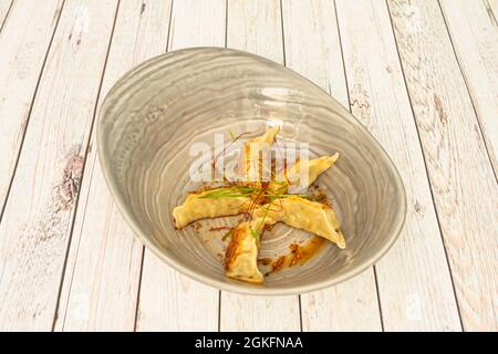 Gyozas ripieni di pollo fritto alla griglia con filamenti di zafferano su una ciotola grigia Foto Stock