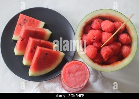 Fette di cocomero fresco. Il suo bene per mantenere il vostro corpo fresco dal calore estivo. Sparare insieme a cucchiai di melone e succo su sfondo bianco. Foto Stock