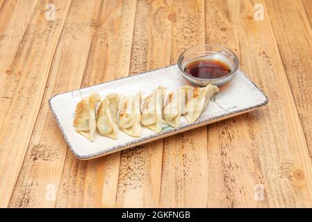 Piatto popolare di gnocchi asiatici fritti gyozas alla griglia con salsa di soia per immergersi su un bellissimo piatto bianco Foto Stock