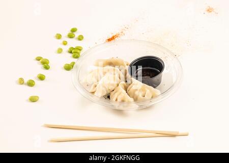 Gnocchi giapponesi ripieni di gamberi, gyozas, al vapore e posti all'interno di un piatto trasparente con bacchette in primo piano Foto Stock
