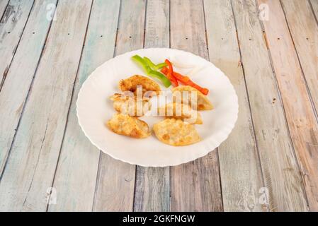 Gnocchi cinesi fritti gyozas farciti con verdure su piatto bianco rotondo Foto Stock