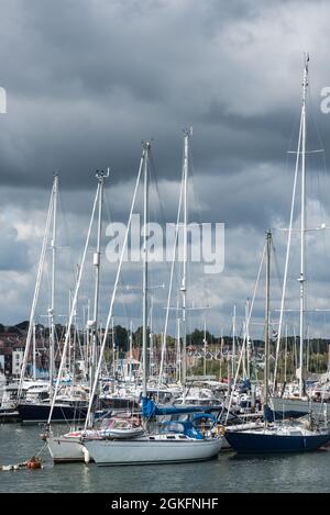 Barche ormeggiate a Lymington, a Hants con l'isola di Wight nel terreno posteriore Foto Stock