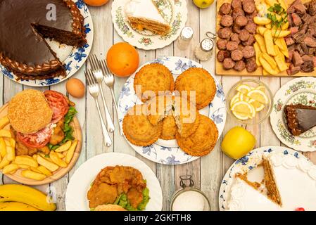 Set di piatti tipici colombiani, torte assortite e hamburger, accompagnati da banane, mele, arance e uova. Foto Stock