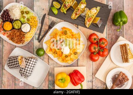 Set di colorati piatti messicani con mais nachos, avocado guacamole, mais dolce, formaggio cheddar, Pico de gallo, croccanti tacos di mais, pomodori a corda, pieno Foto Stock