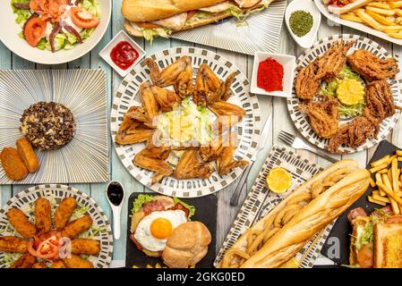 Set di piatti tipici serviti in un ristorante spagnolo con ali di pollo fritte con limone, raba fritta, sandwich con anelli di calamari, prosciutto cr Foto Stock