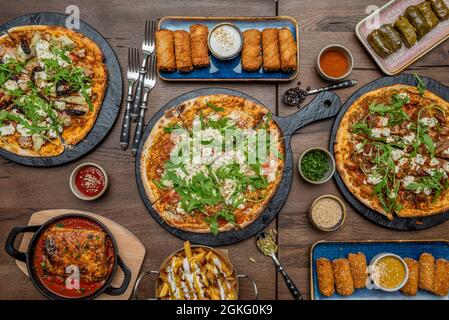 Pizze piccole con molte rucola, lasagne con pomodoro, sarma su piatto rosa, crocchette e panini. Cardamomo, pepe e patate con pancetta e chee Foto Stock