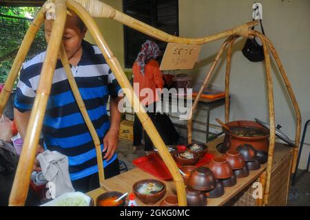 Un soto, una sorta di zuppa tradizionale, venditore sta mescolando soto su una stalla di soto in rattan. Foto Stock