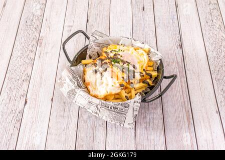 Ricetta Black Bowl ripieno di uova strapazzate con patatine e salsa al tartufo nero su tavola bianca Foto Stock