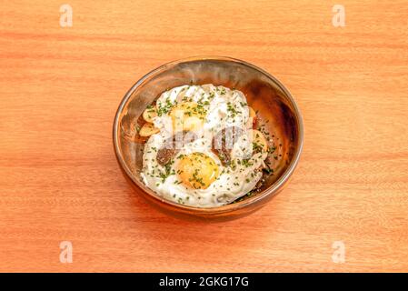 ciotola di uova fritte con salsa al tartufo e patatine e erba cipollina su un tavolo di legno Foto Stock