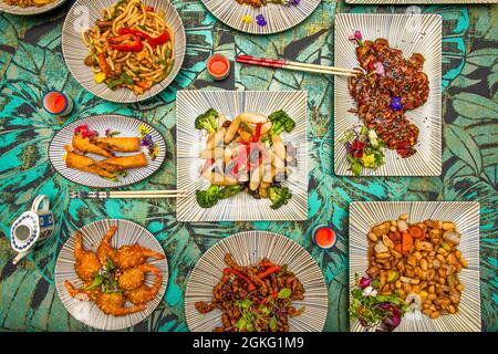 set di piatti cinesi in un ristorante. Lingue di pasta di riso, pollo con mandorle, anatra arrosto, noodle udon, strisce di manzo caramellato Foto Stock