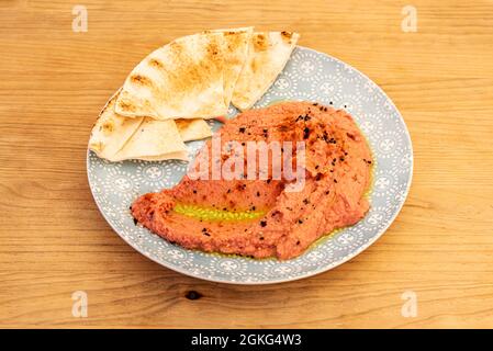 Ceci e hummus di barbabietola con pezzetti di pane azzimo da immergere su piatto grigio e tavola di legno Foto Stock