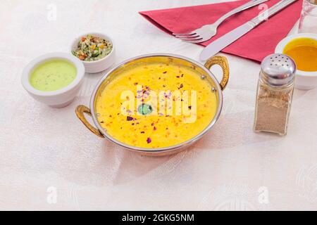 Piatto tradizionale in metallo nei ristoranti indiani e pakistani con una ricetta di korma di pollo con pezzi di verdure e salsa verde da abbinare al Foto Stock