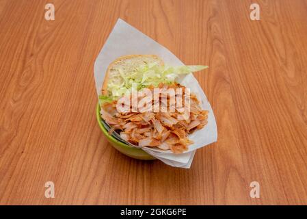 Panino kebab con ciambelle di pollo tritato con lattuga iceberg su tavola di legno Foto Stock